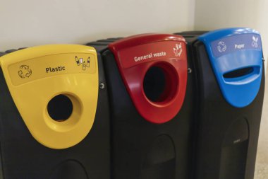 Kamu alanındaki üç atık kutusu açıkça plastik, genel atık ve kağıt için etiketlenmiştir. Çöp bidonları bireyler arasında uygun geri dönüşüm alışkanlıklarını teşvik etmek için renk kodlaması kullanır.