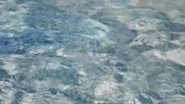 Yumuşak güneş ışığı berrak su yüzeyinde dans eder, parıldayan desenler yaratır. Hafif dalgalanmalar yansımaları bozar, barışçıl açık hava manzarasının sakin atmosferini arttırır. Soyut havuz suyu videosu