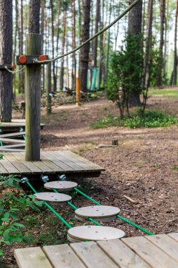 Benzersiz bir ağaç tırmanma parkı keşfetmek için çeşitli aktiviteler sunuyor, ahşap platformlar ve yemyeşil ve uzun ağaçların arasında yükselen elementler, açık hava eğlencesi için mükemmel..