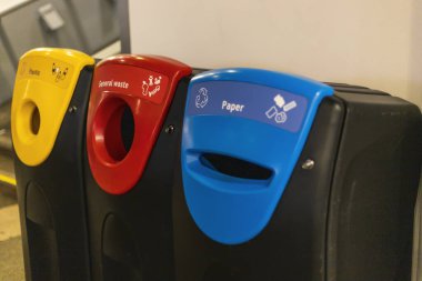 Plastik, genel atık ve kağıt geri dönüşümü için etiketlenmiş üç atık öğütme kutusu birlikte düzenlenir. Atık ayrıştırma için tasarlanmış parlak bir kapalı alanda bulunuyorlar..