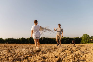 Güneşli bir günde bir adam ve oğlu açık arazide yürürler. Oğul, köpek yakınlarda koşarken ince dallar taşır ve doğada neşeli bir aile oluşturur..