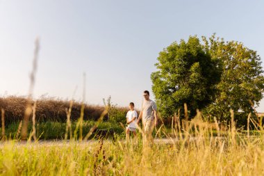 Baba ve oğul sıcak ve güneşli bir günde köpekleriyle gezintiye çıkarlar. Park yeşil çimenler ve ağaçlarla doludur. Huzurlu bir atmosfer yaratır..