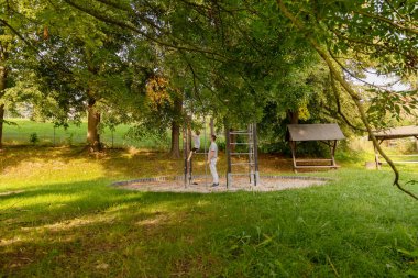 Bir baba ve küçük oğlu yemyeşil bir ortamda oyun parkında oynuyorlar. Büyük ağaçların gölgesinde kahkaha ve bağlılık zamanlarını paylaşıyorlar, doğanın tadını çıkarıyorlar..