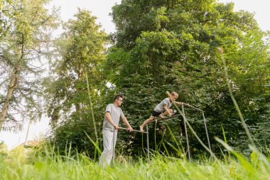 Bir baba oğluna oyun parkında doğal ortamda eğlenirken yardım eder. Güneşli bir günde ağaçların arasında tırmanıp oynadıkları keyifli anları paylaşıyorlar..