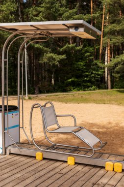 A unique chair enables caregivers to easily assist individuals with disabilities in getting into the lake for a swim. Located by a sandy beach, it provides comfort and accessibility.