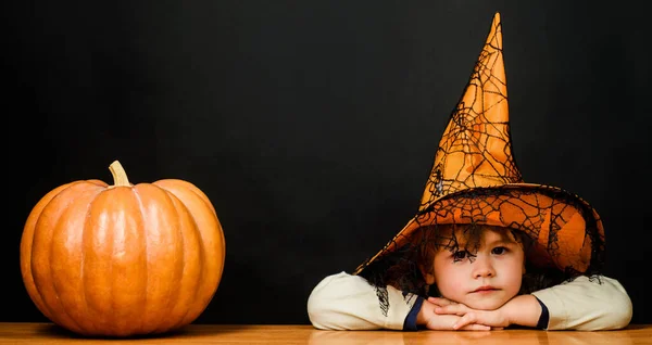 stock image Child in witch hat with pumpkin. Preparation for Halloween celebration. Kids trick or treat
