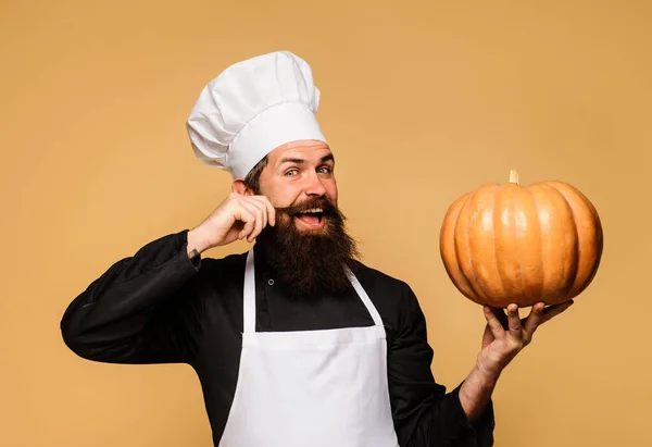 Bearded cook in chef hat with pumpkin. Useful vegetable. Seasonal vitamin. Thanksgiving day cooking