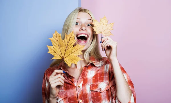 Fashion autumn happy woman with yellow maple leaves. Smiling blonde girl in plaid shirt