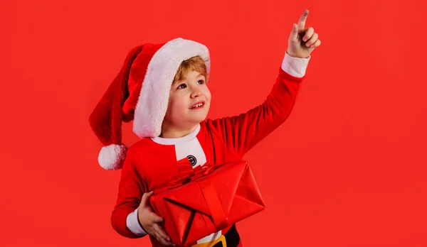 Pomocnik Mikołaja Mały Chłopiec Kapeluszu Świątecznym Pudełkiem Prezentów Wskazującym Przestrzeń — Zdjęcie stockowe