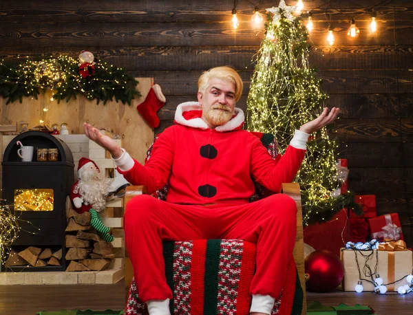 圣诞老人坐在靠近壁炉和圣诞树的房间里的椅子上 圣诞节背景 — 图库照片