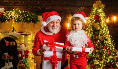 Noel arifesinde hediye kutusuyla küçük bir çocuk ve Noel Baba. Kış aile tatili. Mutlu yıllar.