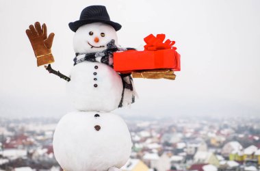 Hediye kutusu el sallayan mutlu kardan adam. Mutlu Noeller ve mutlu yıllar tebrik kartı.