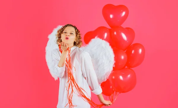 Valentines day cupid. Female angel in white wings with red heart shape balloons sending air kiss