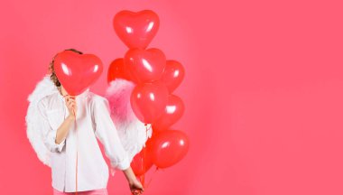 Valentines day. Angel woman in angelic wings with heart shaped balloons. Copy space