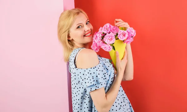 Young woman holds flower bouquet. Happy emotional woman holds flowers. Beautiful girl in trendy dress with flowers in hands. Sexy woman with makeup holds bouquet of roses. Smiling girl with bouquet