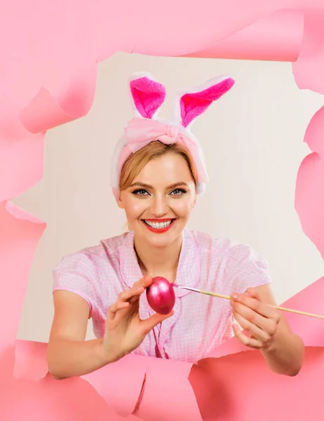 Happy Easter day. Smiling woman in bunny ears painting Easter eggs. Egg hunt. Easter day concept. Happy girl in rabbit ears with painted egg. Bunny woman coloring eggs for easter