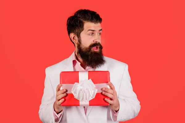 Surprised bearded man with gift box. Businessman with present on Womens or mothers Day, birthday. Handsome male with present box for holiday. Handsome male with birthday present gift