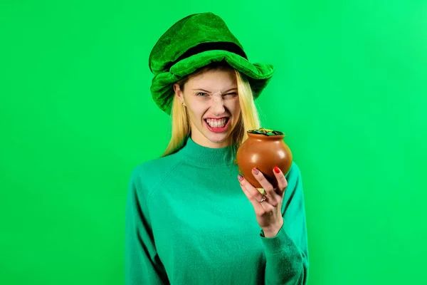 Saint Patricks Day. Irish Traditions. Angry blonde girl in green Leprechaun hat with pot of gold. Saint Patrick Day woman with pot of money. Female in Leprechaun costume with pot of gold coins