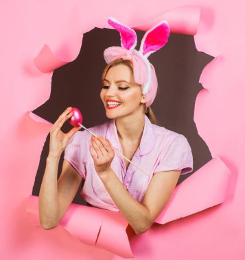 Happy easter day. Smiling woman in bunny ears painting Easter egg. Bunny girl with painted eggs for Easter. Color egg assortment. Sale. Discount. Bunny woman in rabbit ears coloring eggs for Easter