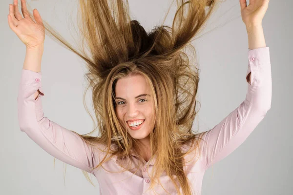 Smiling woman with long disheveled hair. Haircare. Happy girl with waving hair. Fashion woman hairstyle. Female model with messy unbrushed dry hair in hands. Damaged hair, health and beauty concept