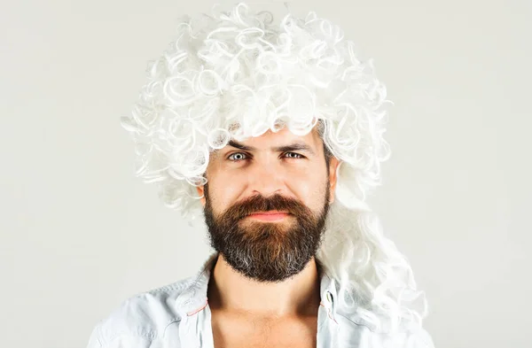 Bearded man in white wig. Smiling man with beard and mustache in curly wig. Bearded hipster in wig. Man in periwig. Party time. Fashion concept. Barbershop advertise. Stylish guy with long white hair