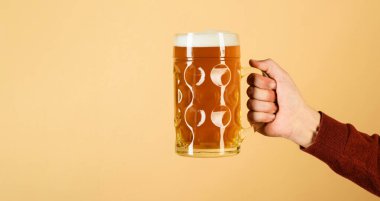 Oktoberfest festivali. Bira kupası tutan bir adam. Bar ya da bar. Kalın köpüklü taze soğuk bira. Bira bardağıyla erkek eli. Bavyera birası. Yarım litre birayla el ele tutuşun. Alkol içeceği. Parti zamanı