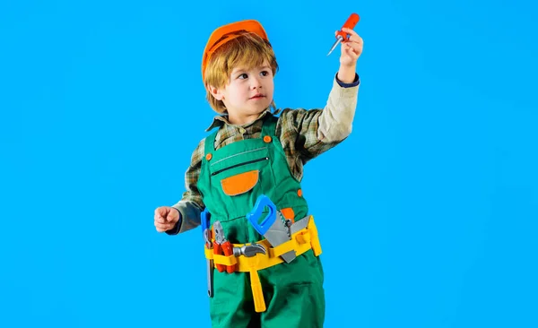Boy in safety helmet and toolbelt with screwdriver. Child game. Little repairman, craftsman or construction worker playing with toy tools for building. Child in builders uniform with tools for repair