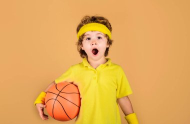 Basketbol topuyla şaşırmış bir çocuk. Spor malzemeleri. Basketbol oynayan sporcu çocuk. Profesyonel spor. Spor giyim sektöründe küçük bir basketbolcu. Spor yaşam tarzı. Basketbol antrenmanı. Çocuk aktiviteleri