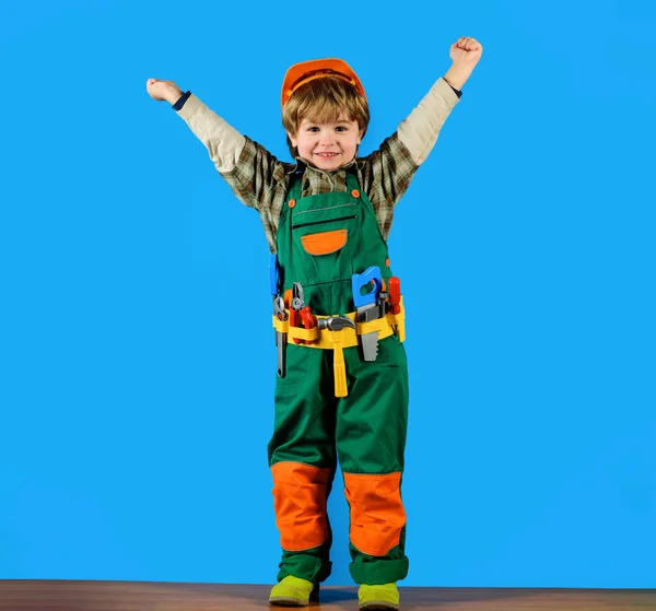 带着头盔和工具带微笑的小男孩举起了手 小修理工 带着建筑工具 穿着建筑工人制服的孩子玩玩具工具 拥有修理工具的建筑工人或建筑工人很少 — 图库照片