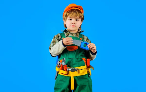 Egy Kisfiú Építőmunkás Egyenruhában Biztonsági Sisakban Fűrésszel Kisfiú Keménykalapban Játékszerekkel — Stock Fotó