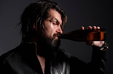 Deri ceketli şık yakışıklı adam bira içiyor. Sakallı adam şişeden bira içer. Elinde bira şişesi olan siyah ceketli vahşi sakallı hippi. Sakallı seksi adam bira içiyor.