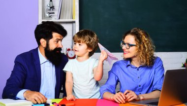 Dersteki küçük okul çocuğu. Evde eğitim. Dersler başlıyor. Gülümseyen öğretmenler ve okul çocuğu yaratıcılık için setle oynarlar. İlkokuldan bir çocuk ve ailesi sınıfta. Aile eğitimi