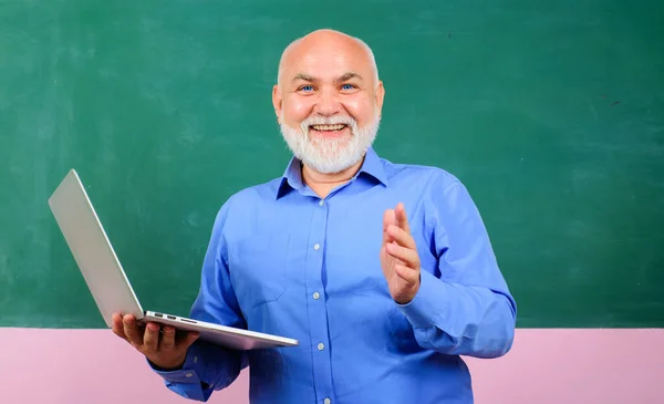 在教室里 用笔记本电脑在黑板前微笑老师 老师给学生授课 大学时的电子学习 在办公室工作的有笔记本的男教师介绍商业培训 — 图库照片