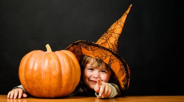 Cadı şapkalı, cadılar bayramı balkabaklı gülümseyen çocuk seni işaret ediyor. Şeker mi şaka mı? Balkabaklı küçük çocuk. Cadılar Bayramı için hazırlık. Mutlu Cadılar Bayramı. 31 Ekim. Cadılar Bayramı kostümlü çocuk