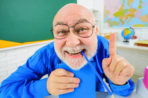 回学校去有趣的老师 带着笔记本 手指向上 戴眼镜的快乐导师 教室里有抄本 教师节 教授给学生授课 高中大学学院 — 图库照片