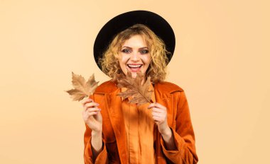 Siyah şapkalı, sonbahar elbiseli, sarı yapraklı güzel bir kız. Sonbahar yaprakları olan şık bir kadın. Turuncu ceketli güzel bir kadın model. Sonbahar kadın modası. İndirim. Kara Cuma indirimi