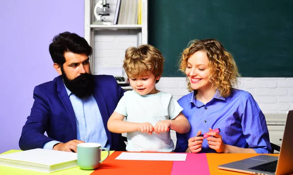 Kid from primary school with parents in school. Teachers helping child from elementary school to make homework. Pupil with parents in classroom. Parenting education. Elementary student ready to study