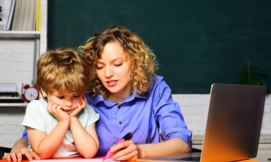 Öğretmenim ilkokuldaki çocuğa yardım ediyor. Ödev yapıyor. Bilgi, öğrenim, eğitim ve öğrenme. İlkokuldaki küçük çocuk derste. Anne okulunda birlikte okuyan bir öğrenci.