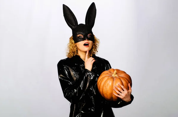 Sexy girl in rabbit mask with Halloween jack-o-lantern. Sensual girl in black leather coat and bunny rabbit mask with Halloween pumpkin. Beautiful woman in Halloween rabbit costume with pumpkin Jack