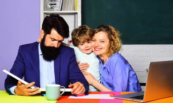 Elementary student. Pupil learning letters and numbers with teachers. Child boy from primary school with parents in classroom. Happy teachers hugging with little schoolboy. Family schooling together