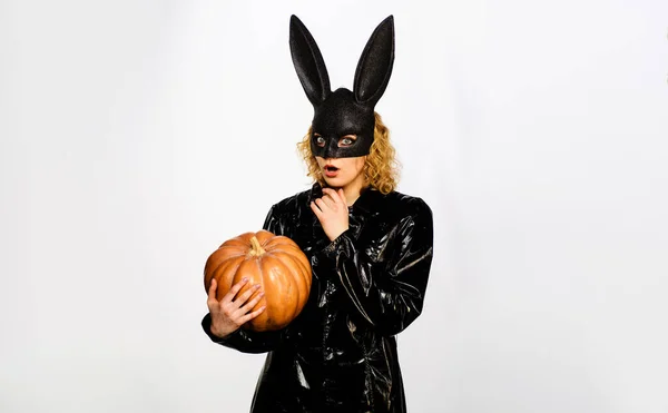 Happy Halloween. Surprised young woman in Halloween costume and bunny rabbit mask with pumpkin. Sensual girl in black leather jacket with Halloween Jack-o-lantern. Preparation for Halloween holidays