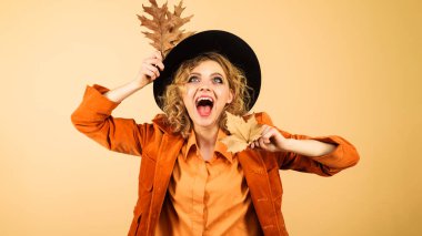 Siyah şapkalı sonbahar mankeni. Sarı yapraklı şık giyimli heyecanlı kız. Kadınlar için sonbahar giysileri. Sonbahar yapraklı turuncu ceketli mutlu kadın. Sonbahar geldi. Sezon satışları. İndirim