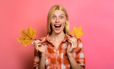 Güz yaprağıyla şık giyinmiş güzel bir genç kız. Sarı yapraklı sonbahar kadını. Sonbahar yaprakları. Kadınlar için sonbahar giysileri. Ekose gömlekli, yapraklı harika bir kadın. Sonbahar indirimi. İndirim