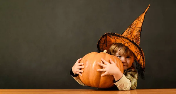 Preparation for Halloween holiday. Thanksgiving day cooking. Little child boy in witch hat with Halloween pumpkin. Halloween kid with jack-o-lantern pumpkin. Trick or treat. Halloween sales. Discount
