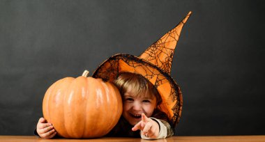 Cadılar Bayramı. Cadılar Bayramı balkabağı seni gösterirken cadı şapkalı gülümseyen çocuk. Şeker mi şaka mı? Cadılar Bayramı için hazırlık. Jack-o-feneri olan küçük çocuk. Cadılar Bayramı indirimi. İndirim. Reklamcılık