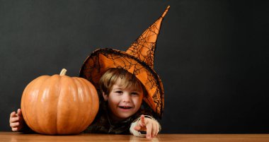 Cadılar Bayramı. Cadılar Bayramı balkabaklı, cadı şapkalı, gülümseyen çocuk. Küçük büyücü, sihirbaz Cadılar Bayramı tatiline hazırlanıyor. Elinde balkabağı feneri olan küçük bir Cadılar Bayramı çocuğu. Sonbahar indirimi. İndirim. Reklamcılık