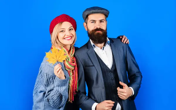 Autumn couple. Stylish couple in fashionable wear. Relationship. Smiling girlfriend hugging with boyfriend. Autumn fashion. Happy woman in knitted sweater, scarf and hat with bearded man in suit
