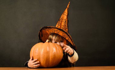 Mutlu Cadılar Bayramı. Cadılar Bayramı tatiline hazırlanan balkabağı fenerli küçük çocuk büyücü. Cadılar Bayramı şapkalı, gülümseyen çocuk ve balkabağı seni işaret ediyor. Cadılar Bayramı satışları. İndirim