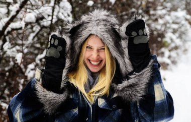 Karlı kış parkında ceketli, şapkalı ve eldivenli mutlu bir kız. Dışarıda şık giyinmiş, gülümseyen kadın. Soğuk hava. Kışın kürk şapkalı ve ceketli güzel bir kadın manken. Kış modası