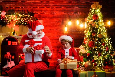 Aile tatilleri ve çocukluk. Noel Baba ve Noel Baba 'nın küçük yardımcısı Noel için dekore edilmiş odada hediyeleri var. Noel Baba ve çocuk Noel ağacının yanında Noel hediyeleriyle. Yeni yıl kutlaması